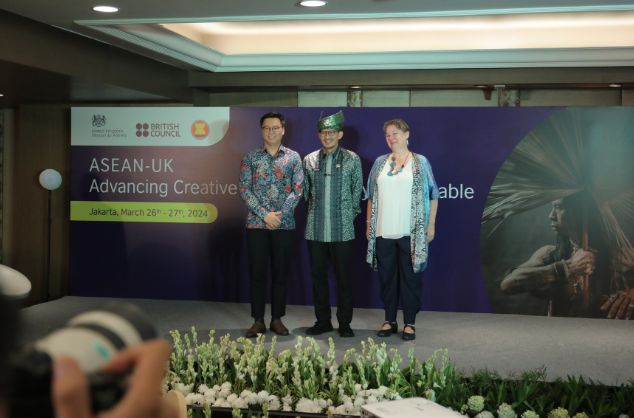 Three people are photographes as they stand on a stage at the ASEAN conference