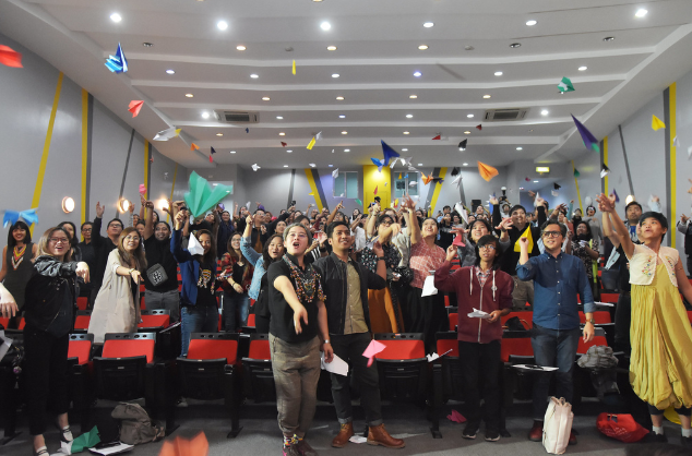 A lecture of theatre full of delegates who are throwing paper planes