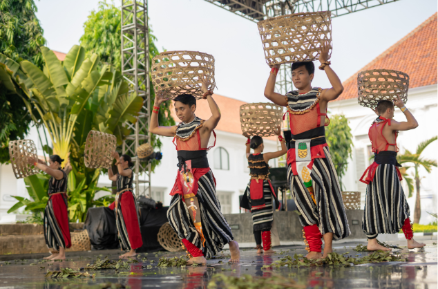 Six men stand holding baskets in a performance in Indonesia