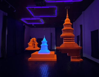 An augmented reality display showing a fluorescent orange and blue hologramic display over the top of a dark gallery space. 