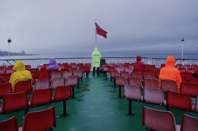 Film still of people in raincoats aboard a boat