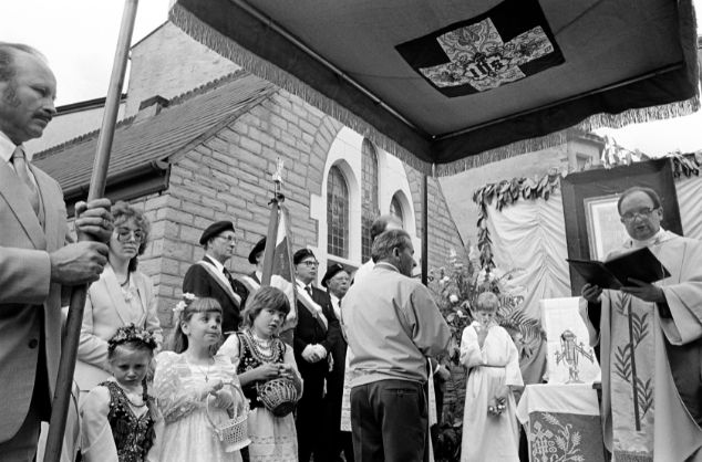 A black and white photo of a priest and some of the congregation at a Polish mass.