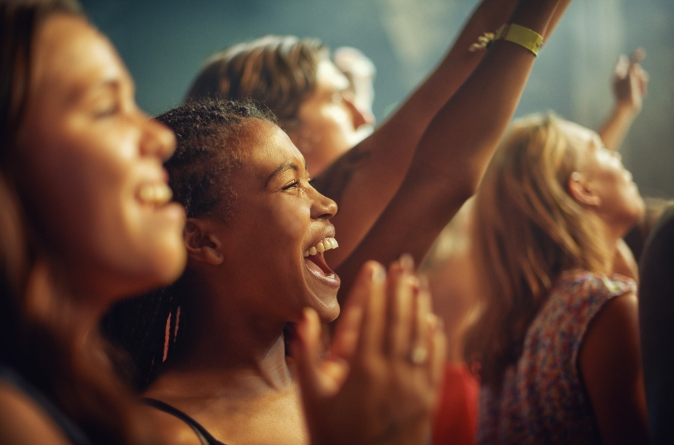 Close up of ladies in crowd, cheering, arms in the air.
