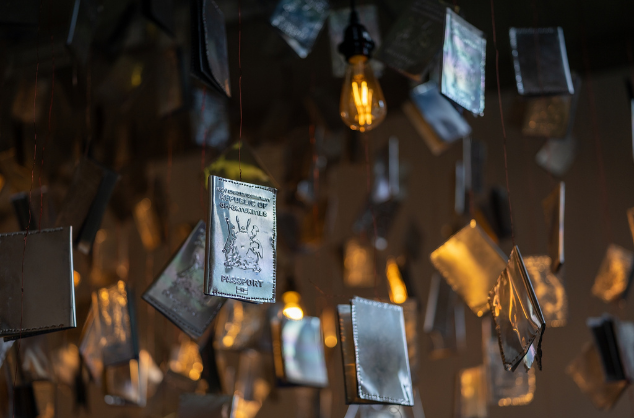 Many grey passports hanging down, some lit from beneath with a gold light.