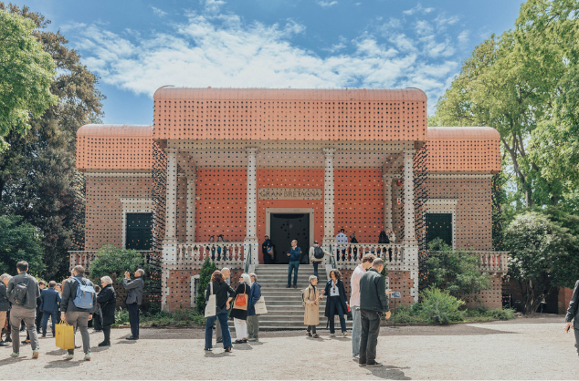 Visitors standing outside an exhibition on a bright day.
