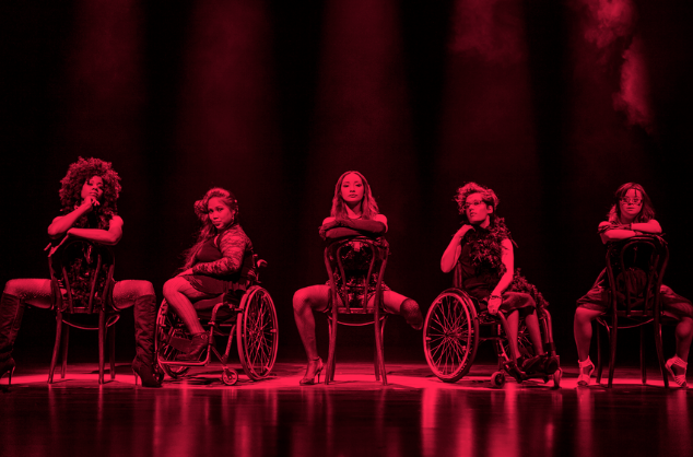 Five disabled artists lined up on stage performing Chicago. The image is tinted red and black. 11 Million Reasons to Dance inspired by Chicago, People Dancing. Photo: Sean Goldthorpe 