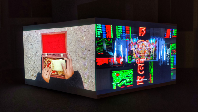 Two screens at angles next to each other, one showing hands inside a box of jewellery and the other showing bright city lights.