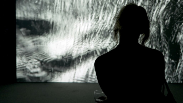 Shadowy image of someone facing a large piece of black and white art.