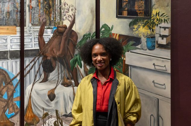A woman smiles at the camera with her large scale painting behind her