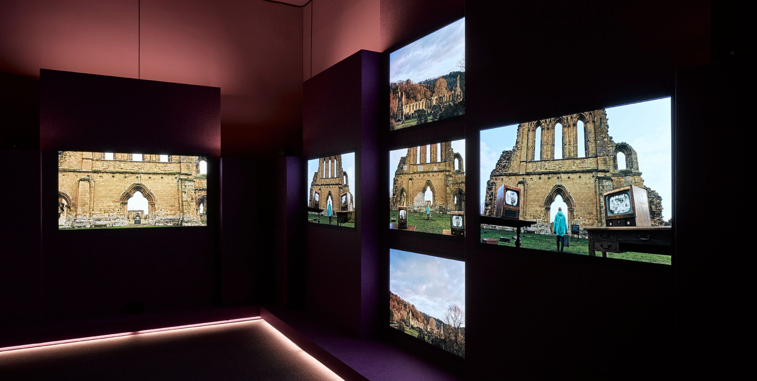 A still from John Akomfrah's Listening All Night To The Rain featuring 6 screens all showing different views of a ruined church.