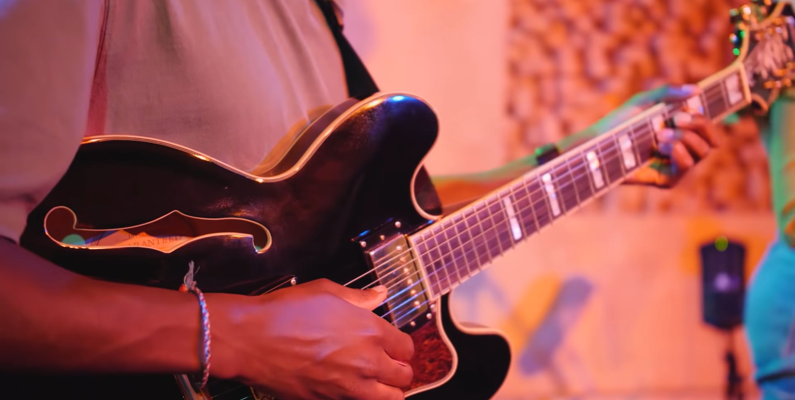 A hand plays a guitar in a studio setting