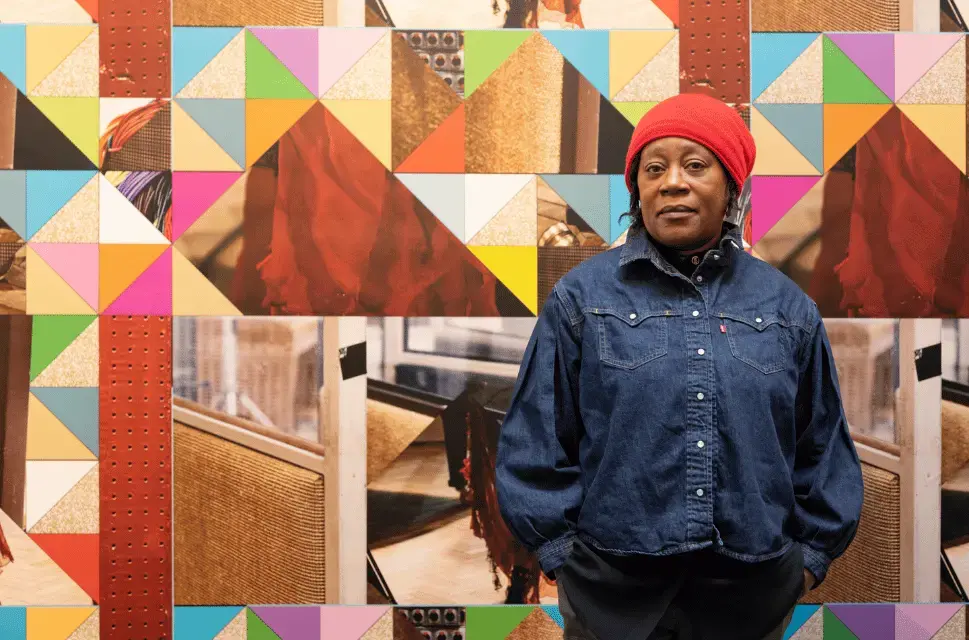 Sonia Boyce stands in front of an artistic installation consisting of coloured triangles of varying sizes in tesselated configurations. Photo by Cristiano Corte (c) British Council