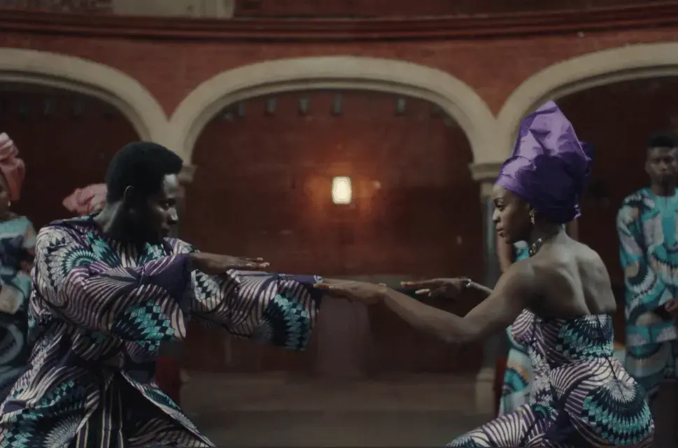 A still from the film work Don't Look at the Finger by artist Hetain Patel. British Council Collection  © Hetain Patel. Two performers engaged in stage combat, dressed in West African ceremonial dress.