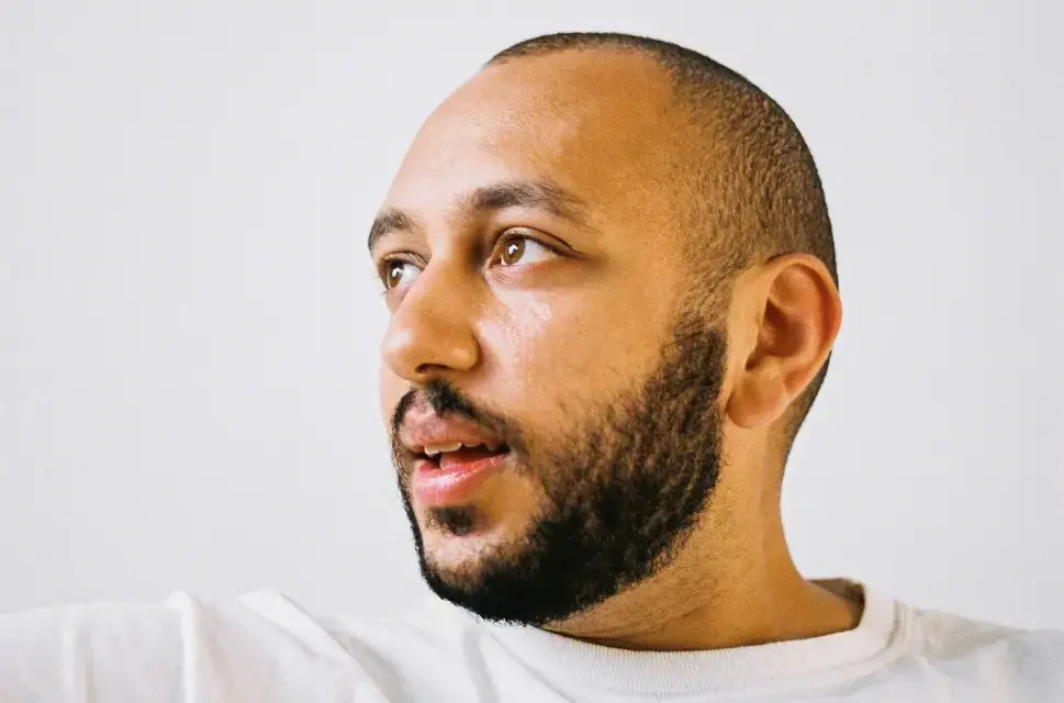 Close up of man with very short hair and beard, looking left.