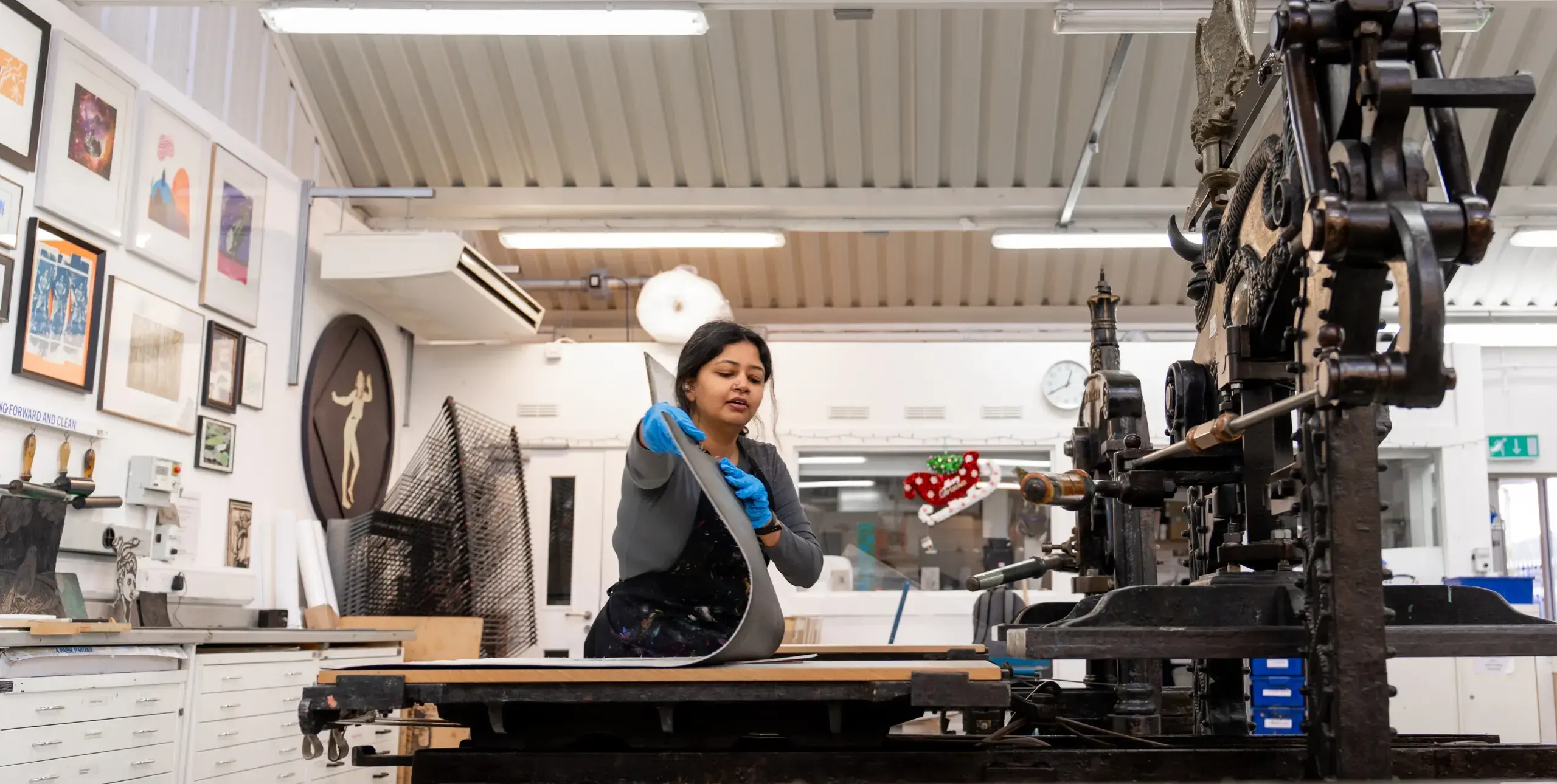 Lady laying down a sheet in an office next to tall vintage machinery.