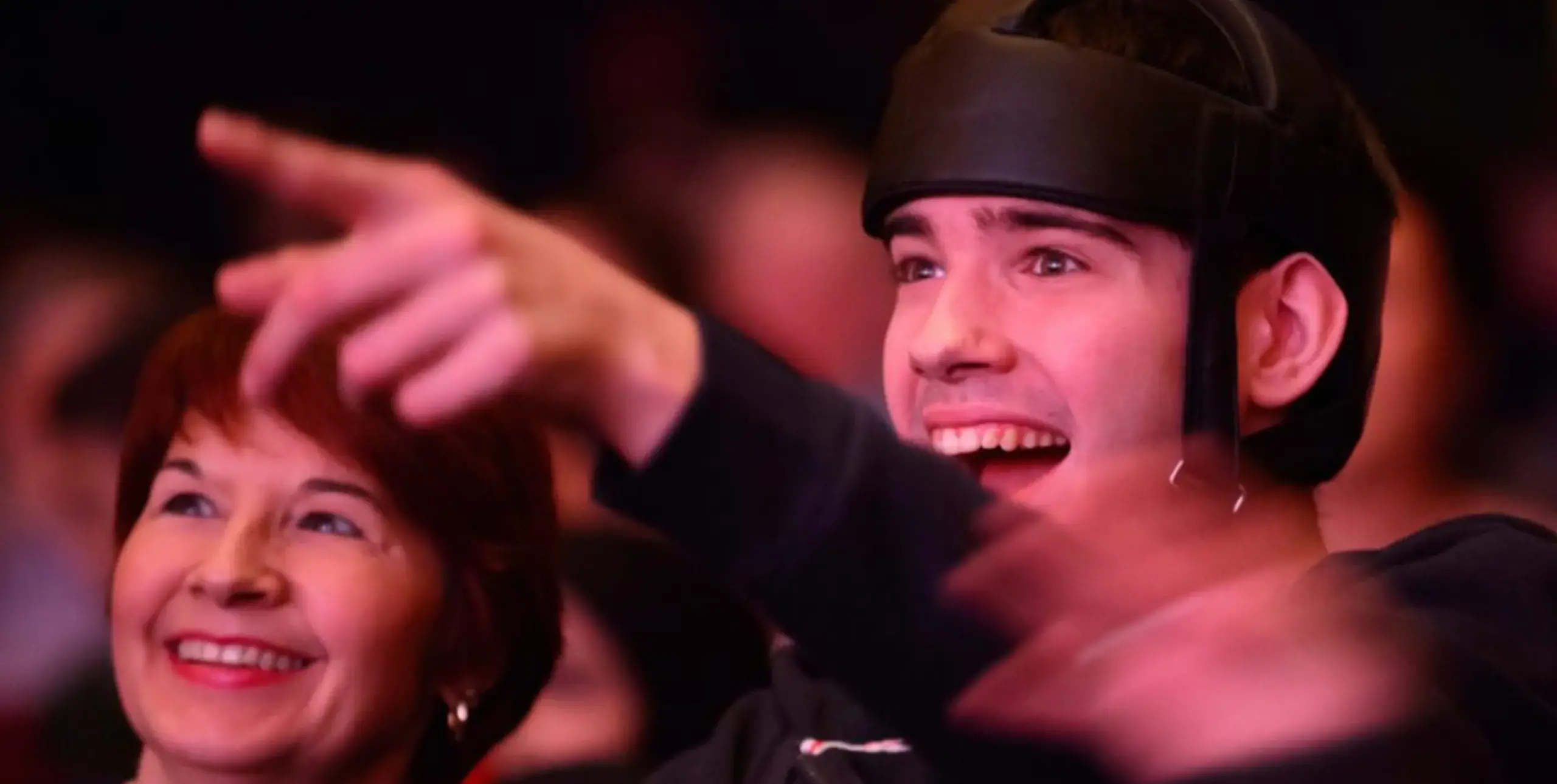 White learning disabled man pointing from a theatre crowd.