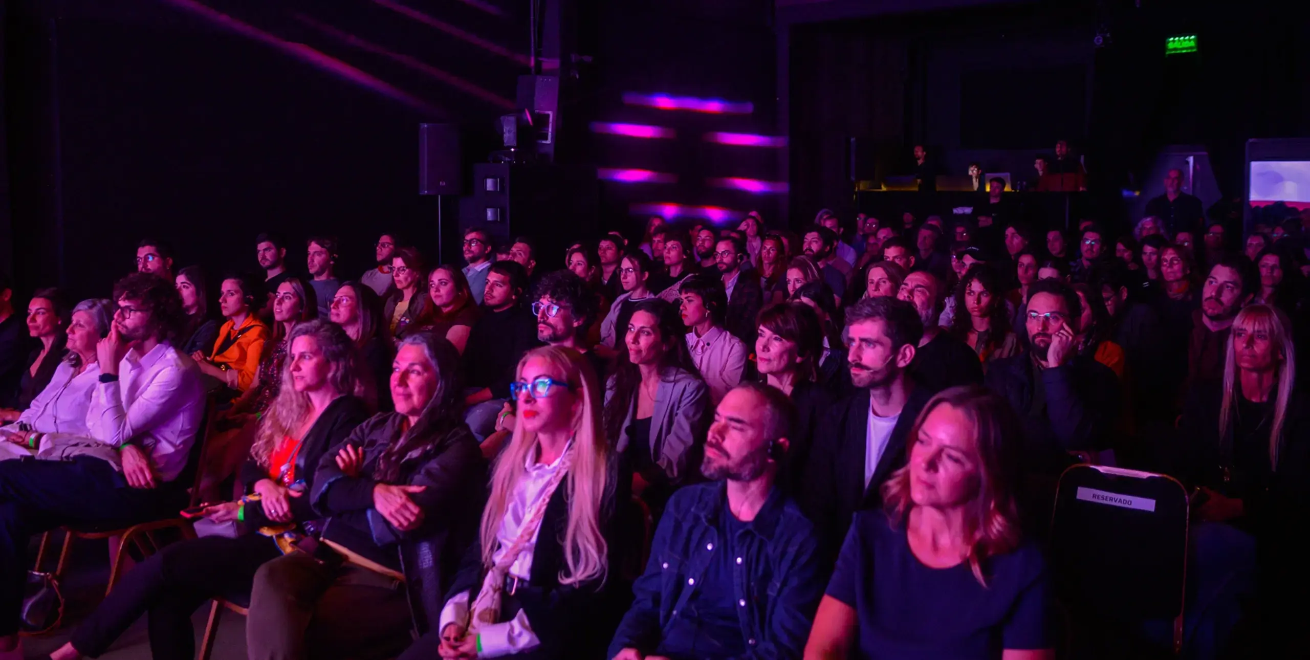 Many people facing a bright screen we can't see.