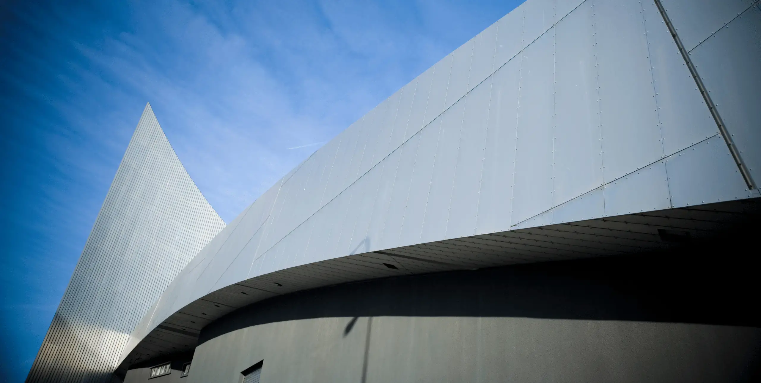 Facade of Imperial War Museum North, Salford, Manchester, England, UK, against a bright blue sky