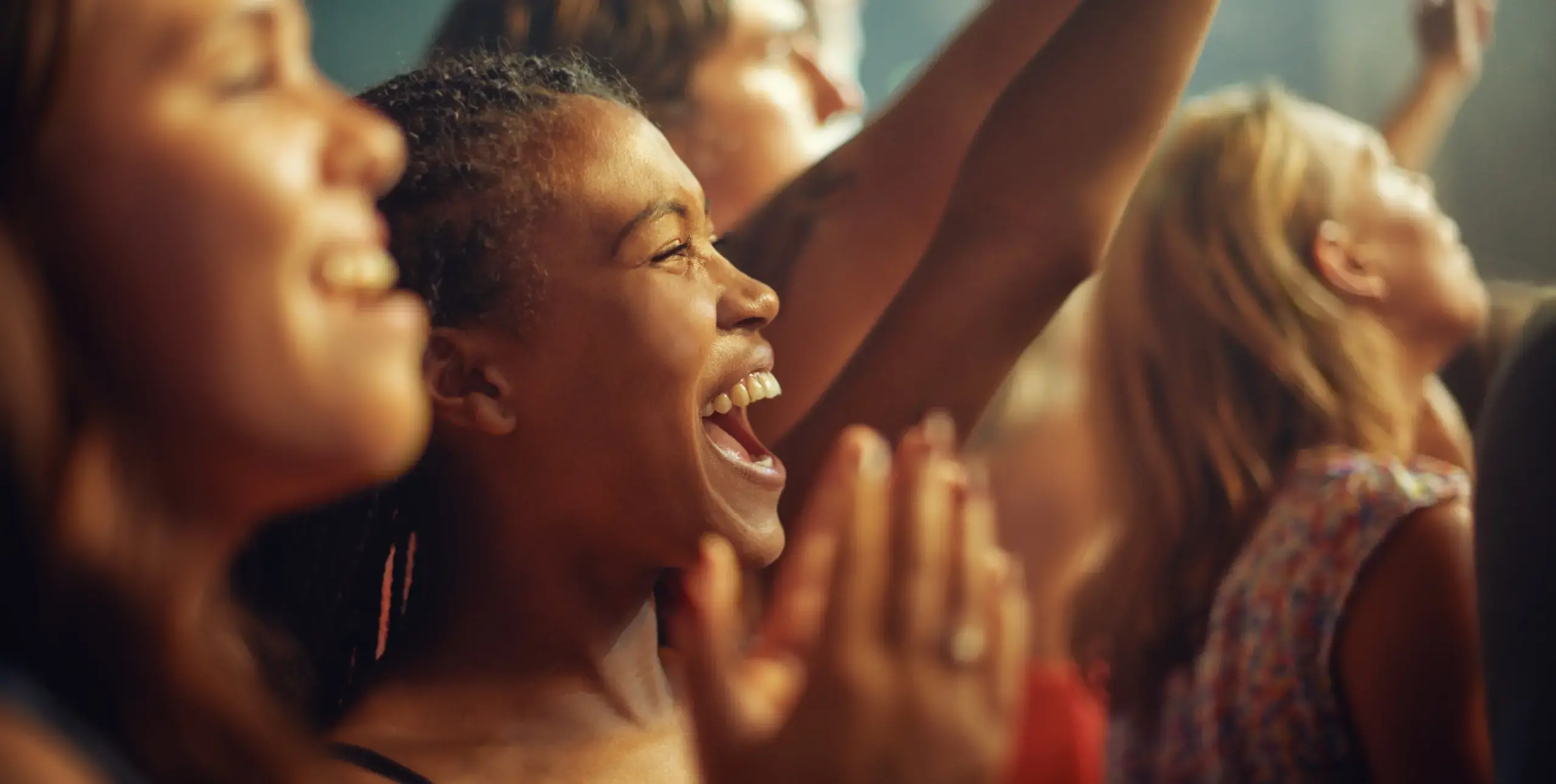 Close up of ladies in crowd, cheering, arms in the air.
