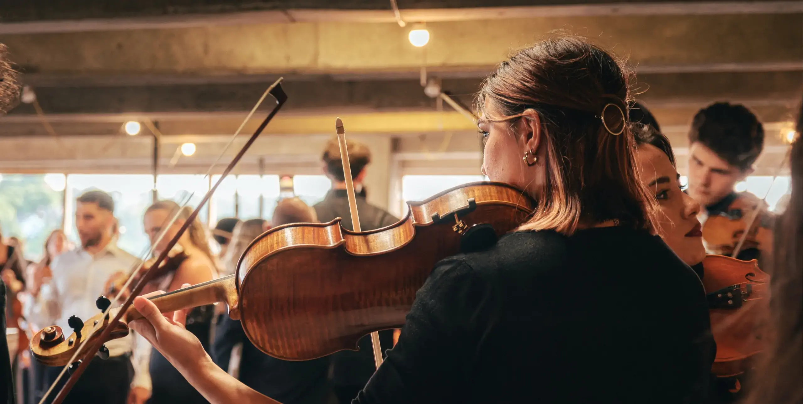 Close up on a lady playing a violin with others blurred around her