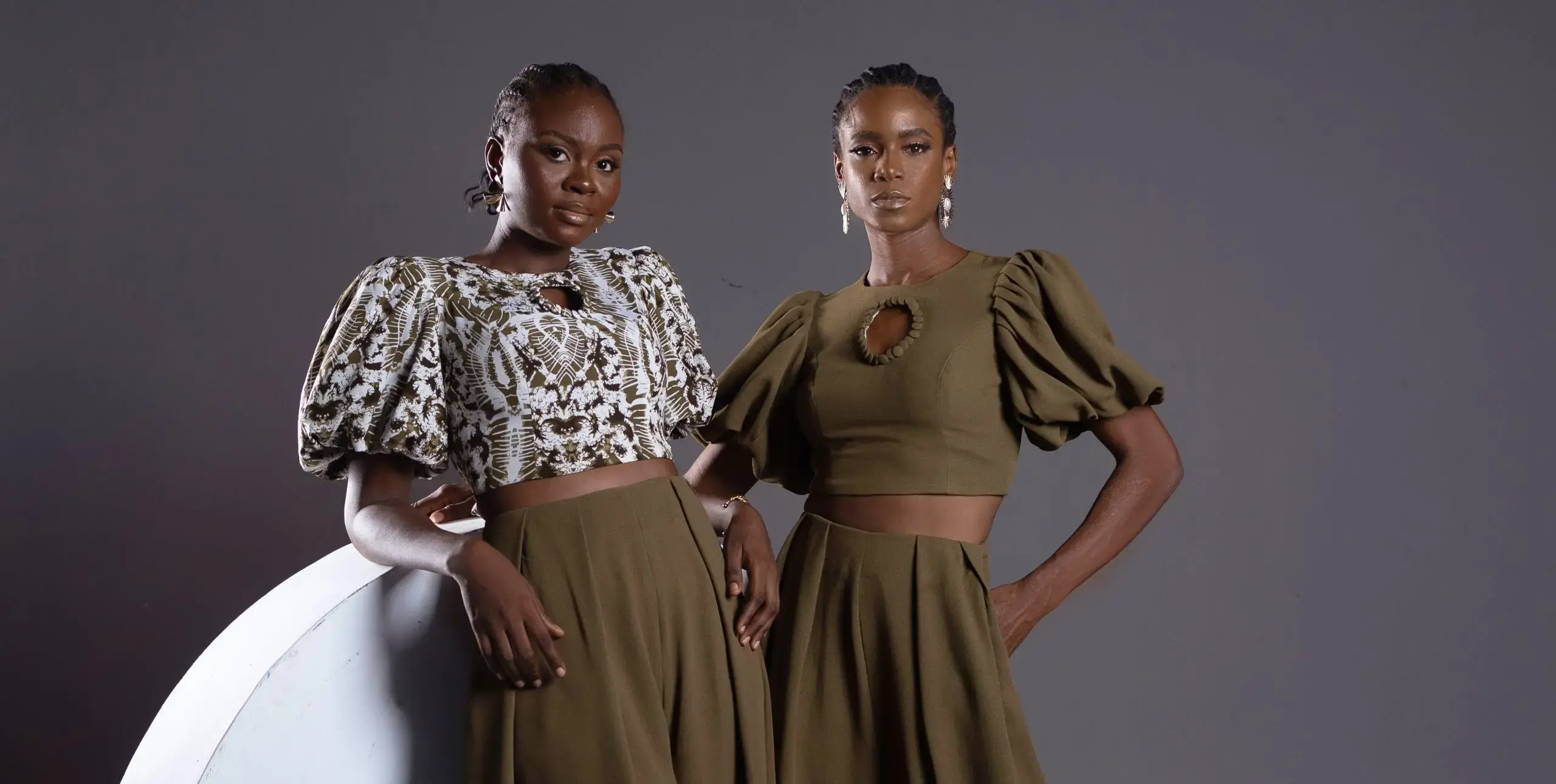 Two models pose in voluminous blouses and skirts