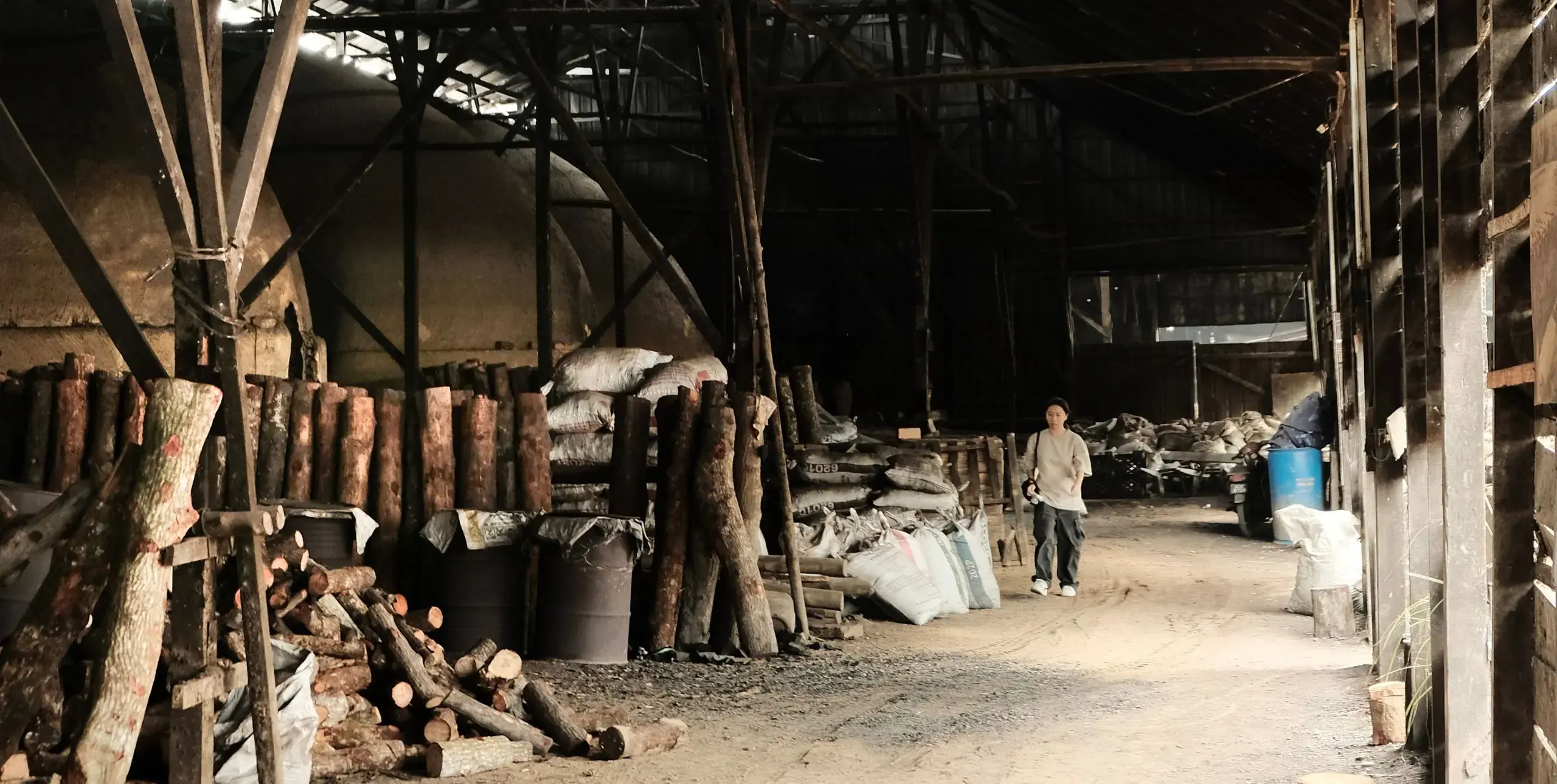 A person walks through a warehouse piled with wood