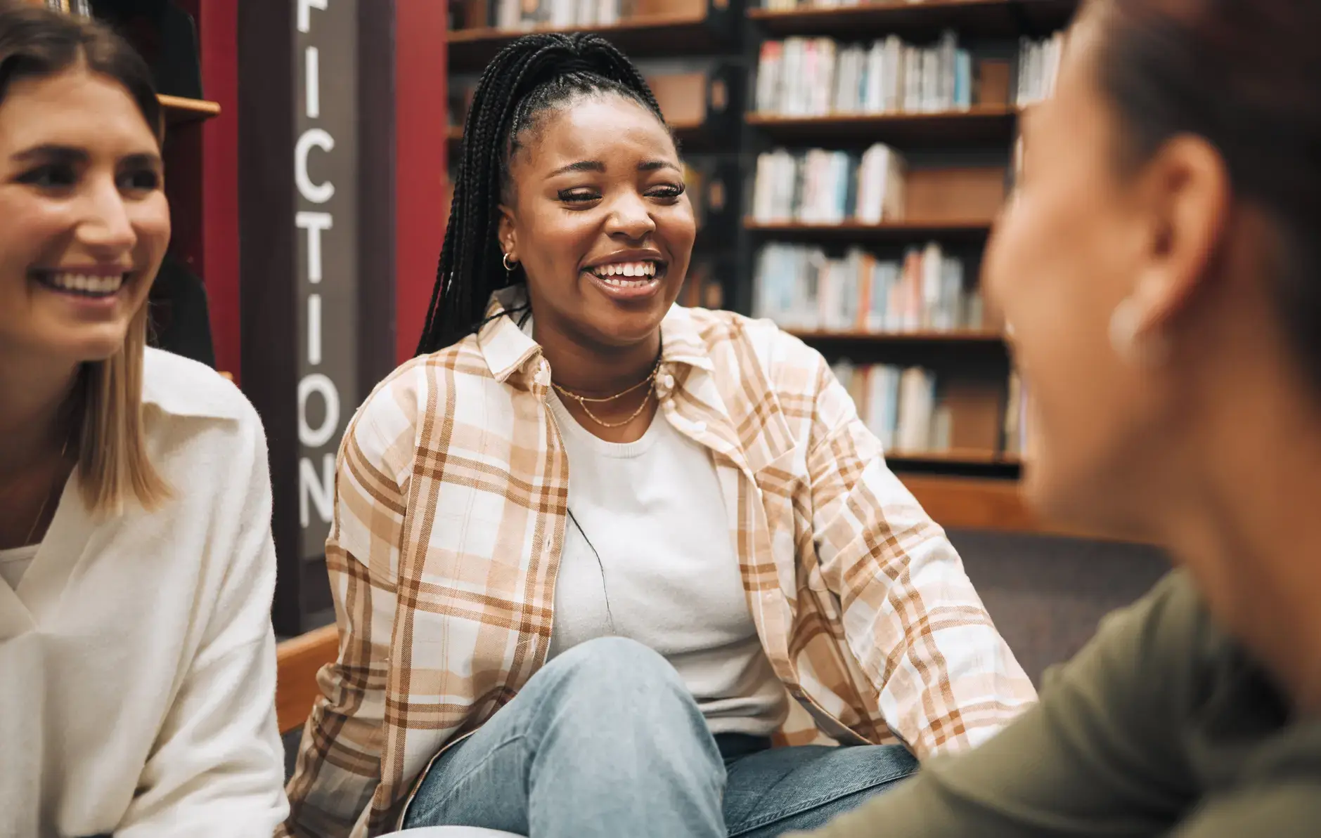 Three women in conversation in a library.