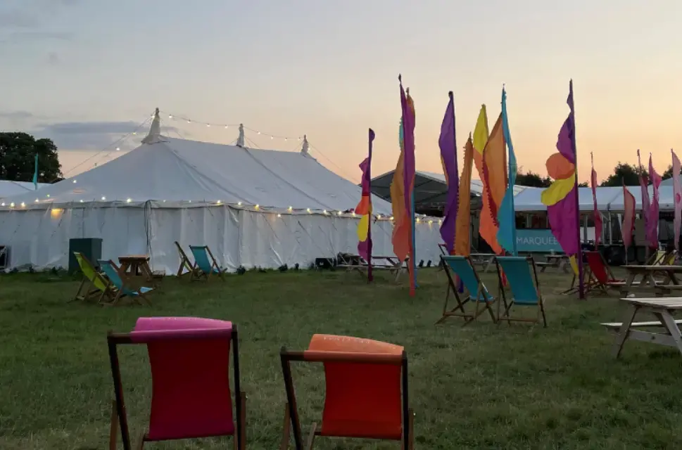 Two deckchairs and a festival tent surrounded by coloured flags taken at dusk from the Hay Festival Wales