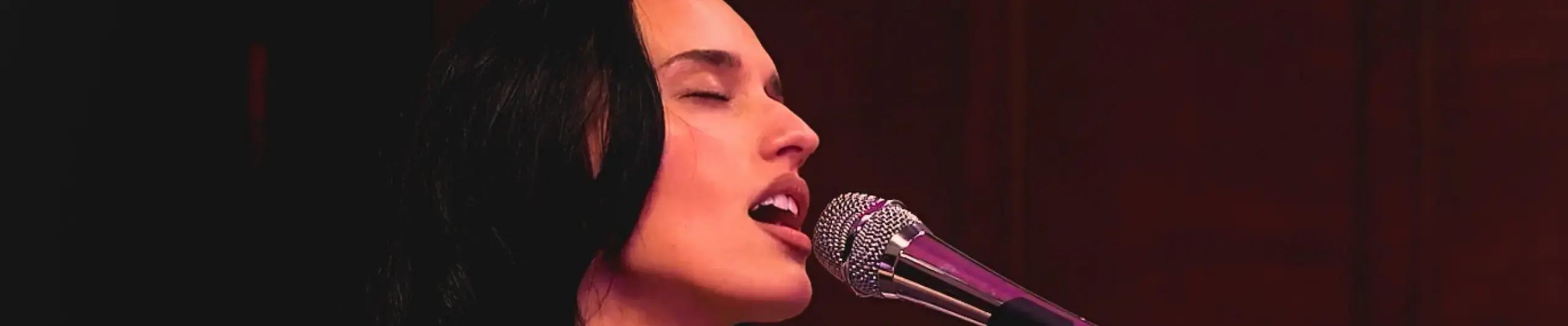 Lady singing into microphone with eyes closed.