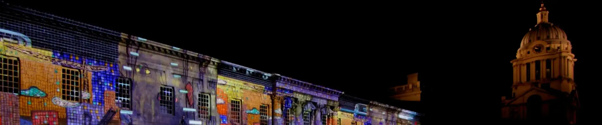 A row of buildings are lit up with a colourful light projection