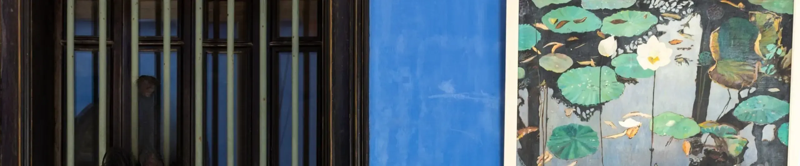 Very close up of an interior showing a blue wall and a picture of flowers.