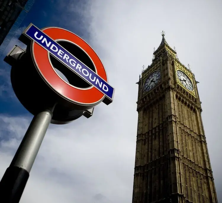 London underground sign on left and Big Ben clock tower rises to the right