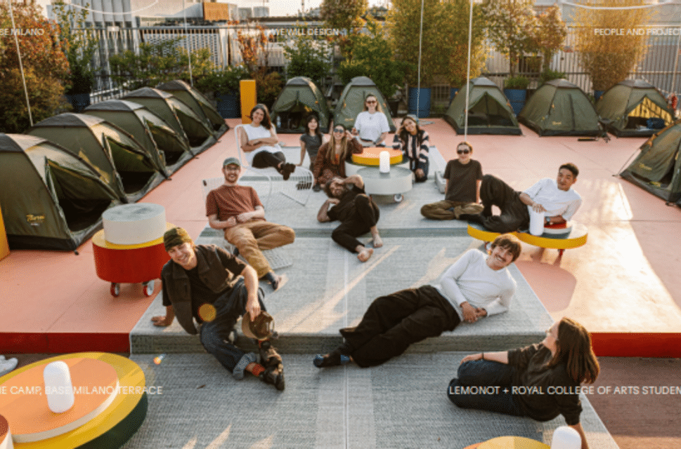 A group of people sat on a red floor surrounded by green tents.