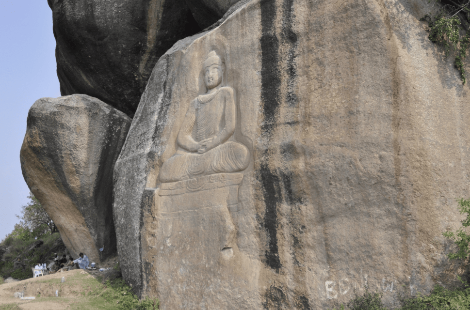 An image of The Buddha carved into the side of a large boulder or mountainside