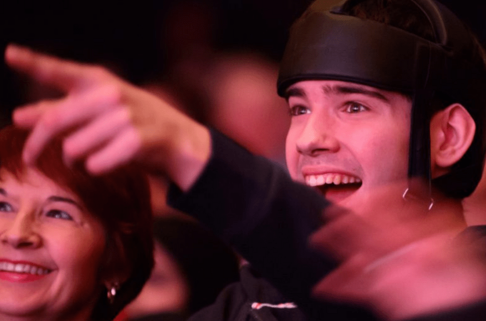 White learning disabled man pointing from a theatre crowd.