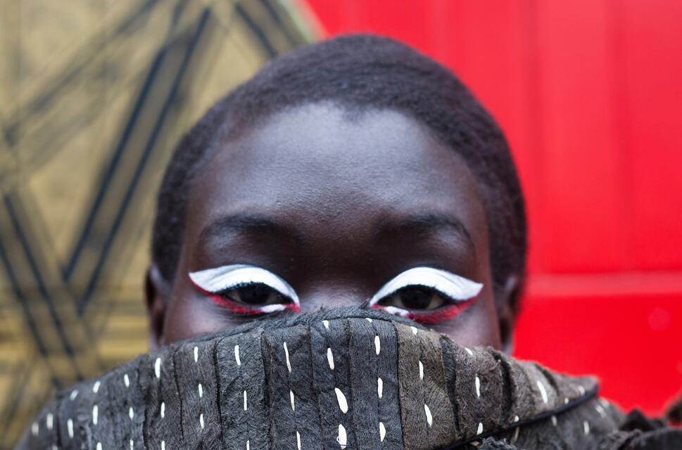 Striking eyes with white eyeliner stare over the top of a woolly scarf for a fashion photo shoot