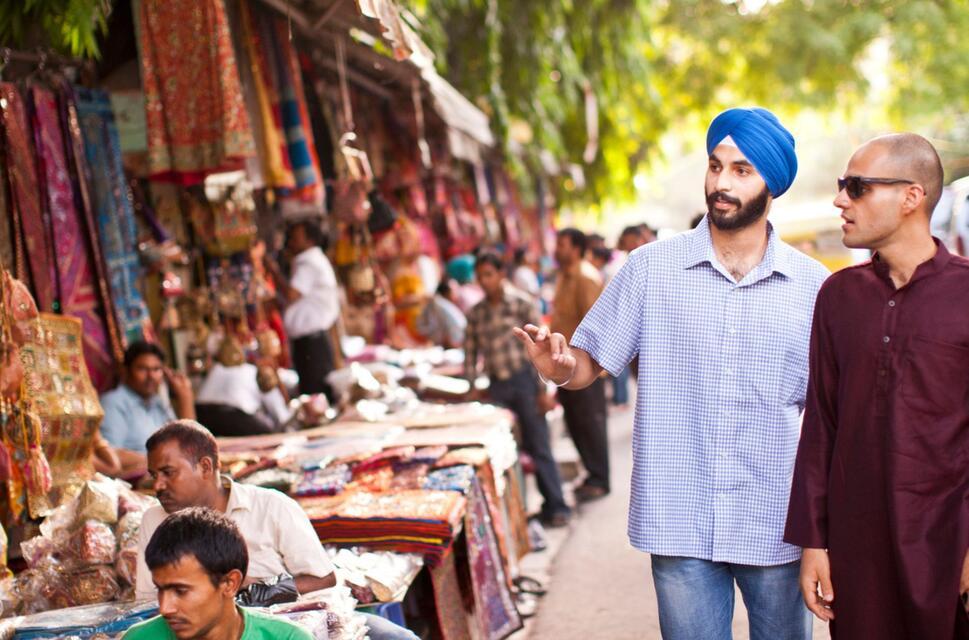 Two men pass a row of stalls selling handicrafts in an Indian city