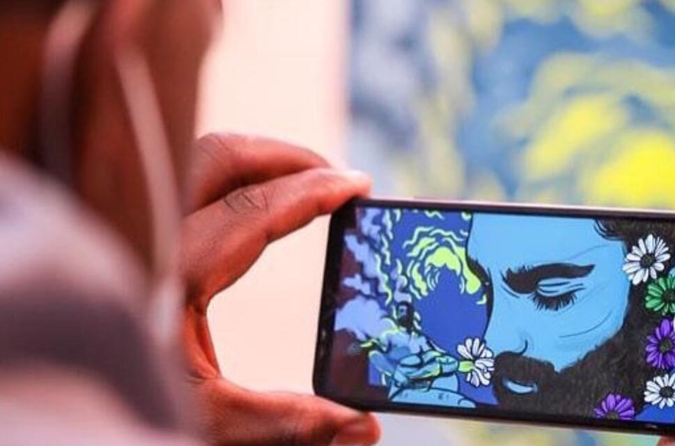 A man takes a picture of a vibrant blue and white artwork at an art gallery.