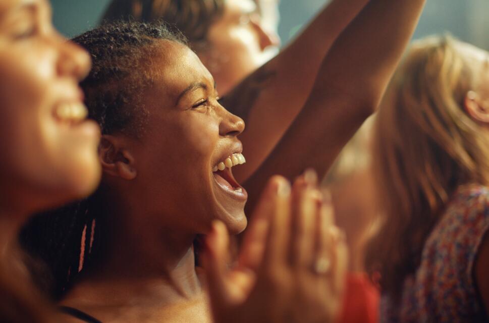 Close up of ladies in crowd, cheering, arms in the air.